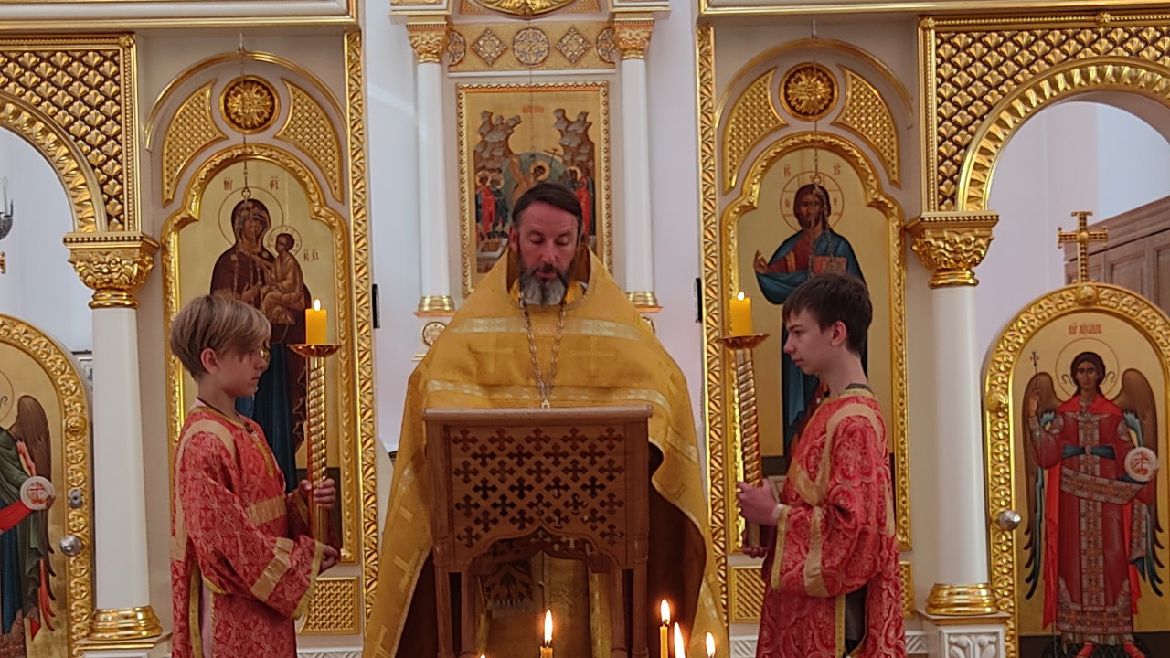 Священник Кирилл Краснощёков по центру читает Евангелие. Справа и слева от него два мальчика алтарника.